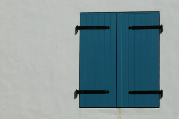 Scuri in legno blu chiusi su parete bianca